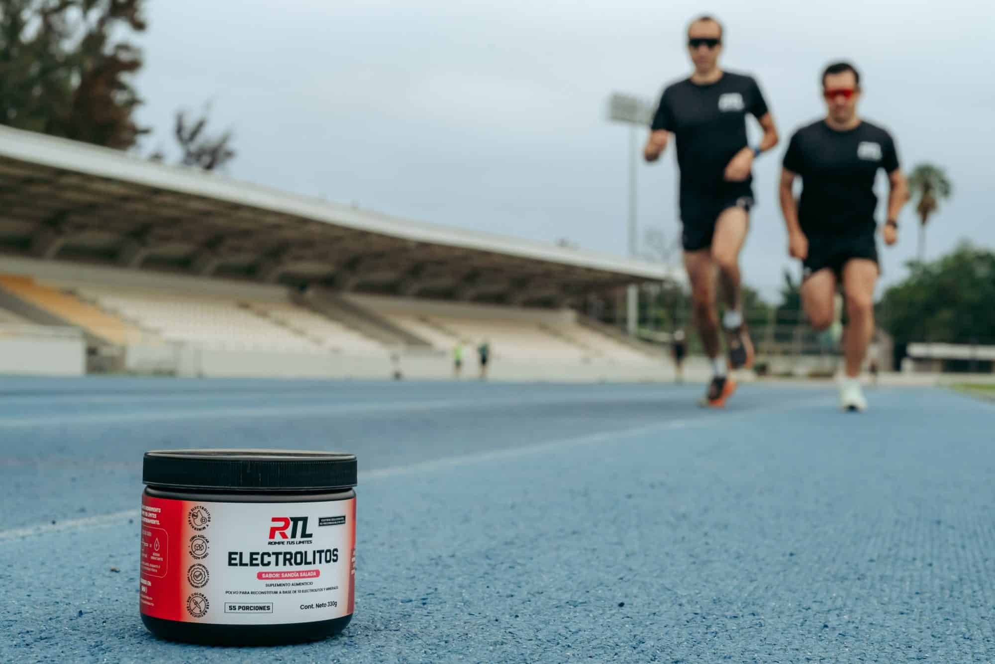 Envase de Electrolitos RTL en la pista con dos corredores al fondo
